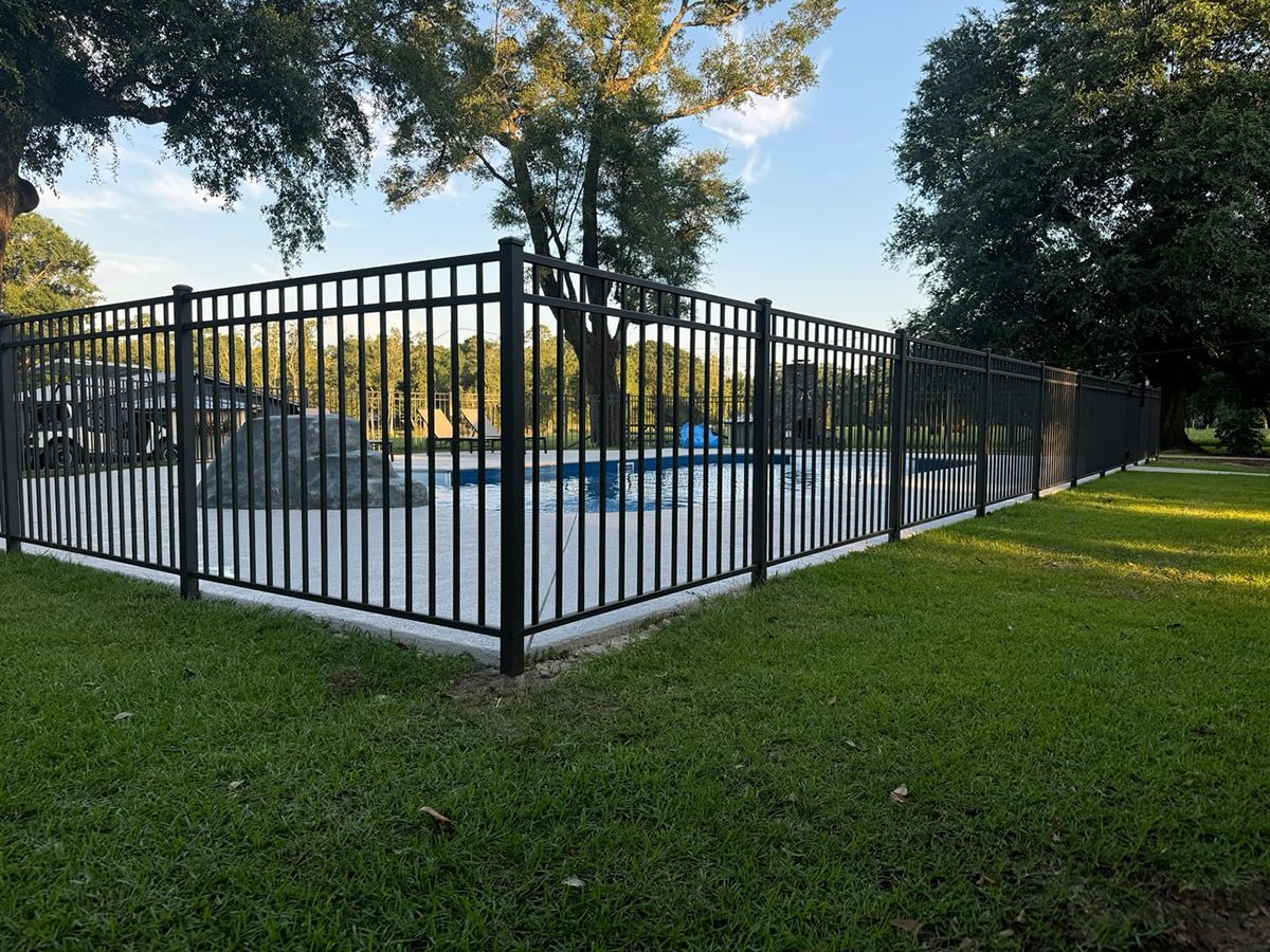 A black fence surrounds a swimming pool in a park.