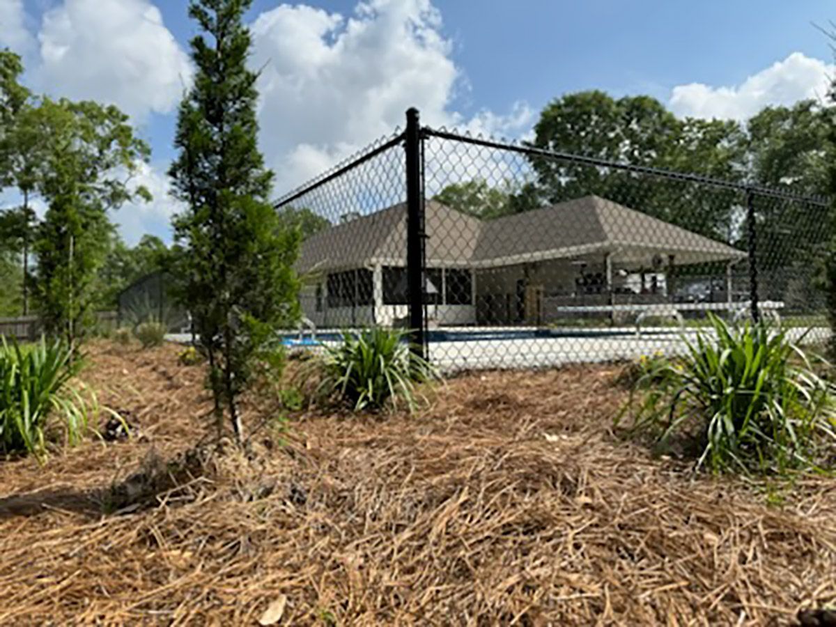 A chain link fence surrounds a house and a pool.