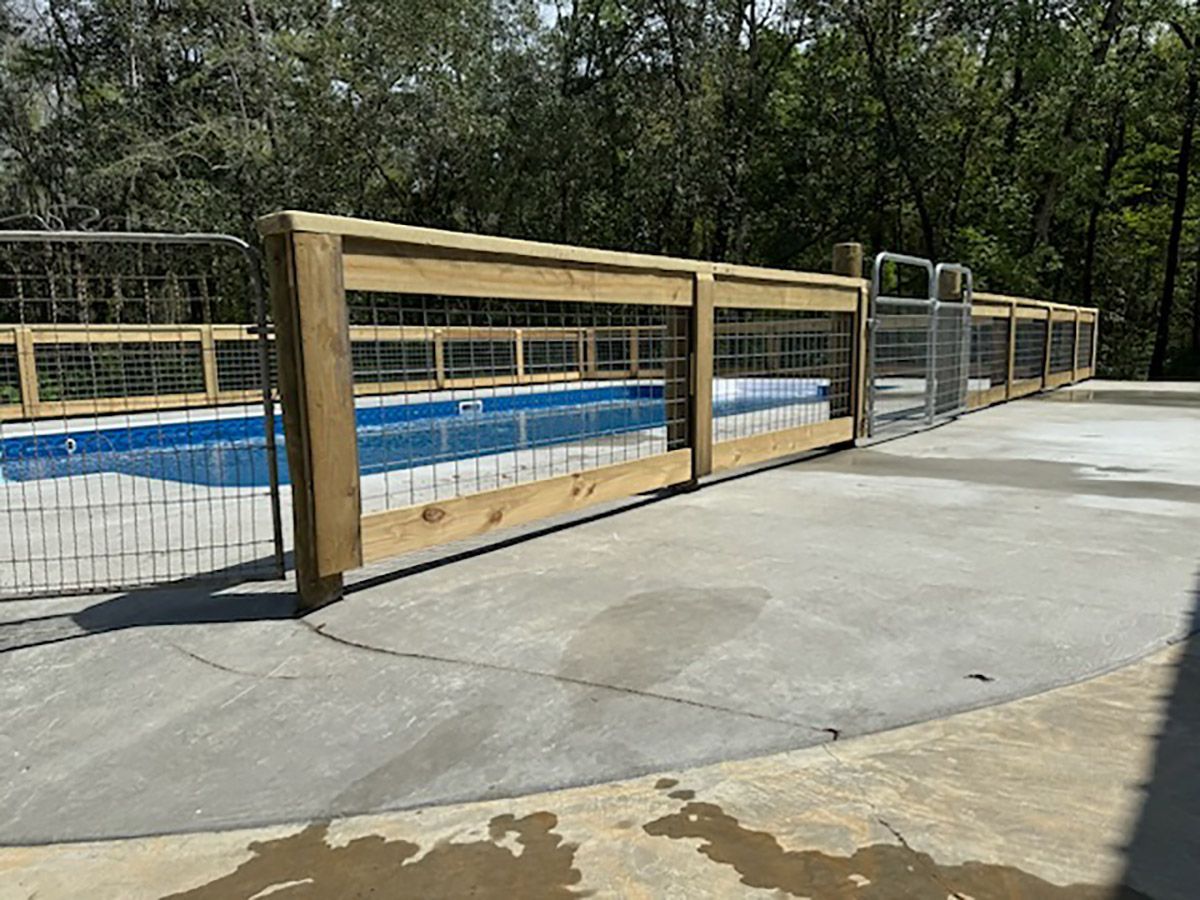 A wooden fence surrounds a swimming pool.