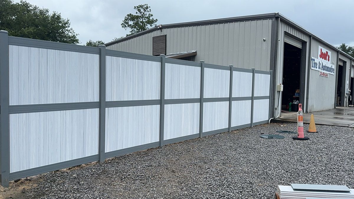 A white and gray fence is in front of a building.