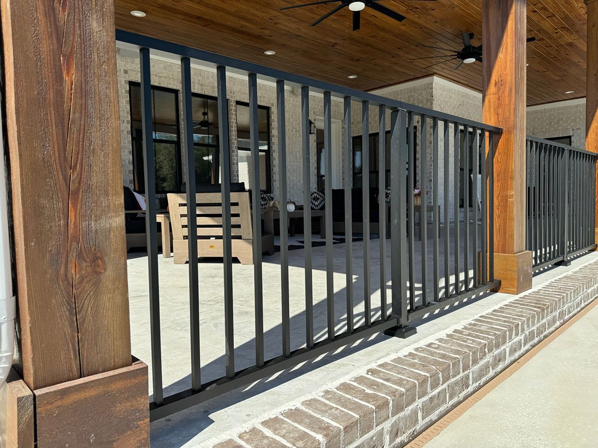 A metal fence surrounds a patio with a ceiling fan.