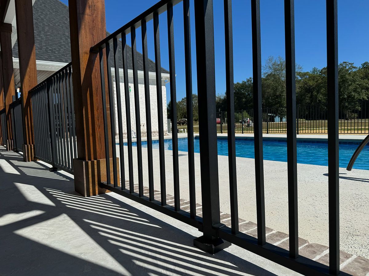 A black metal fence surrounds a swimming pool.