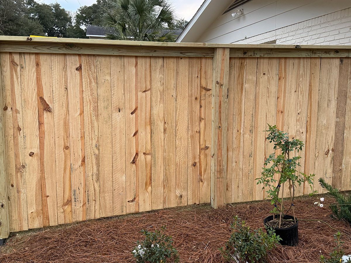 A wooden fence is sitting in front of a house.