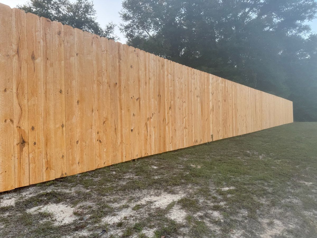A long wooden fence is sitting in the middle of a grassy field.