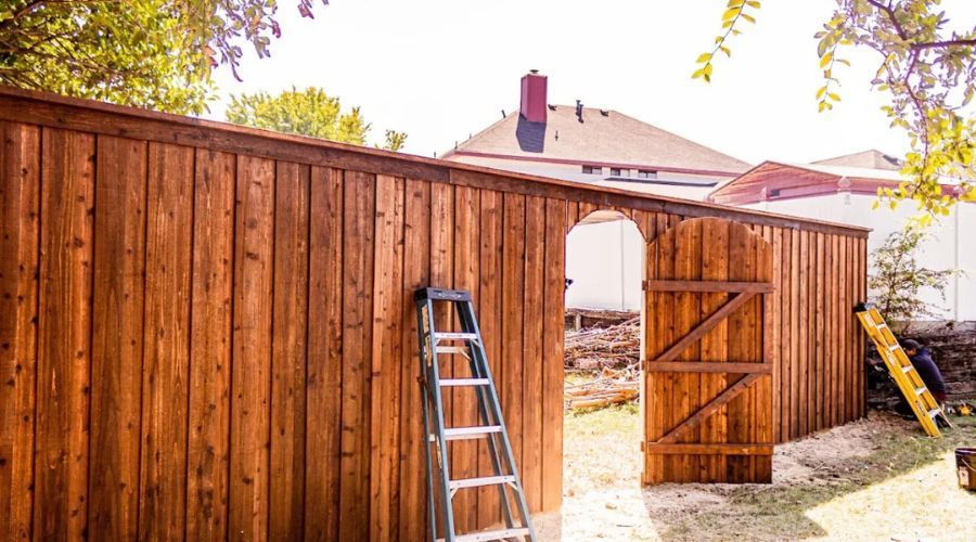 Stained wood privacy fence featuring an open arched gate.