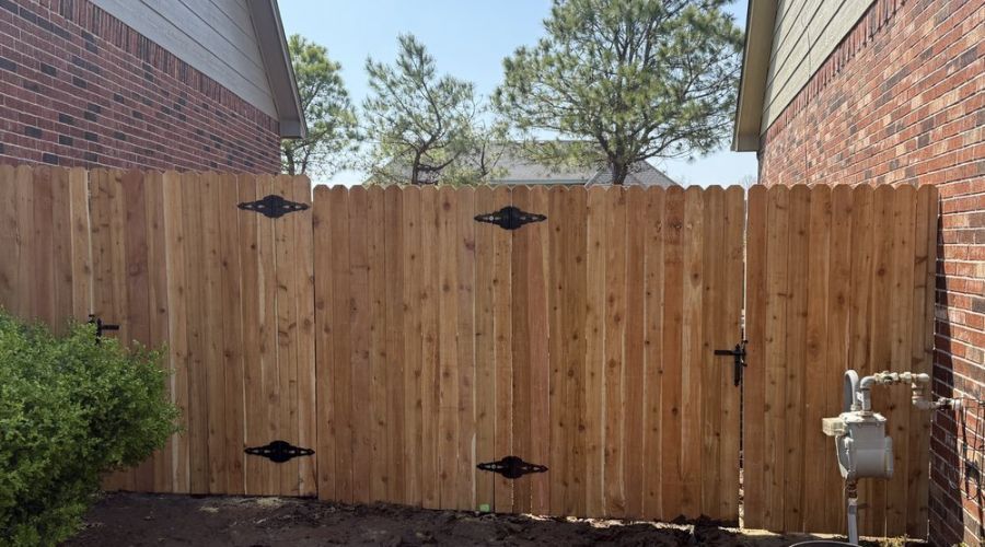Natural wood privacy fence with double gates and black hinges.