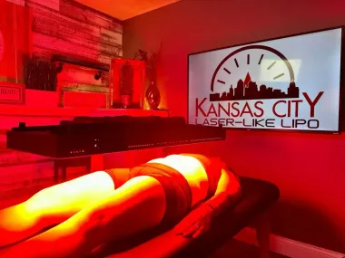 Person undergoing laser-like lipo treatment. Red light illuminates the body in a Kansas City spa setting.