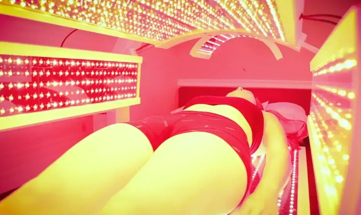 Person lying under red light therapy bed.