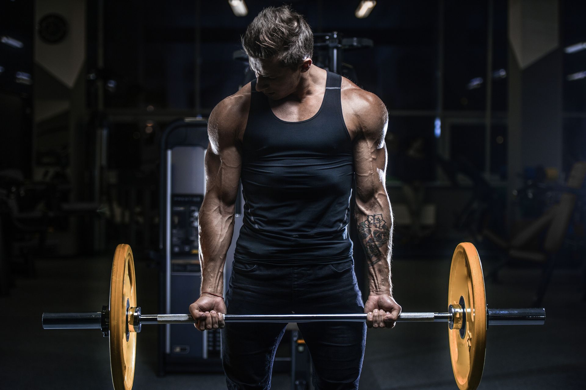 Man lifting a barbell in a gym, with focus on biceps.