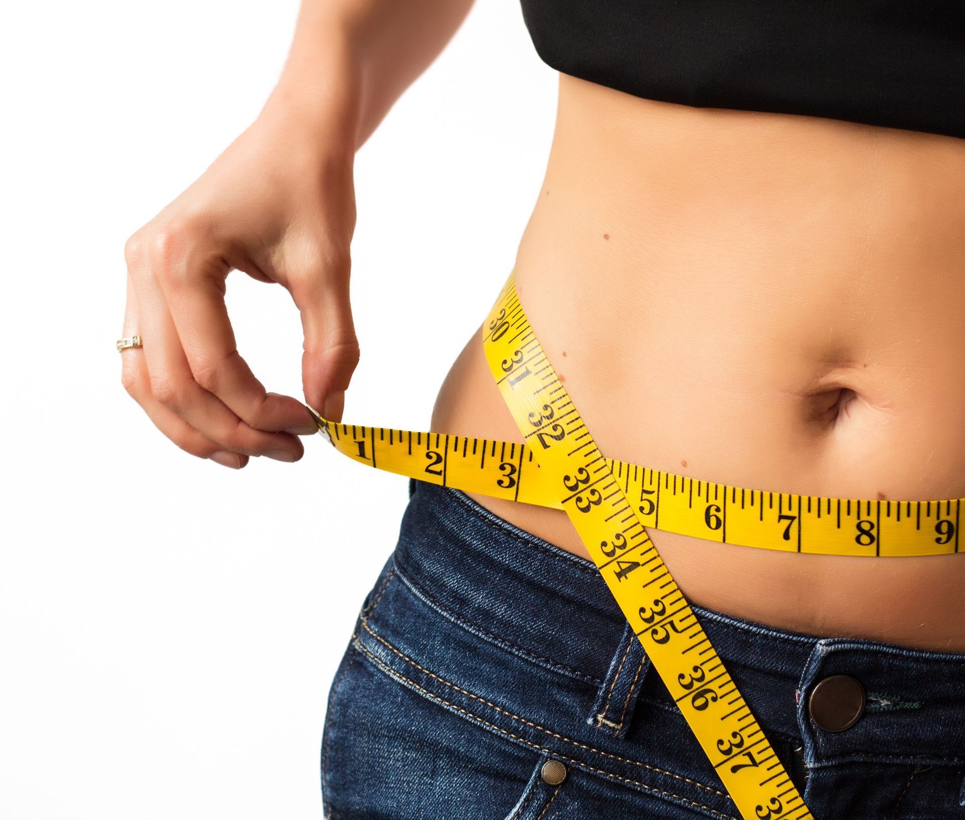 Woman measuring waist with yellow tape measure.