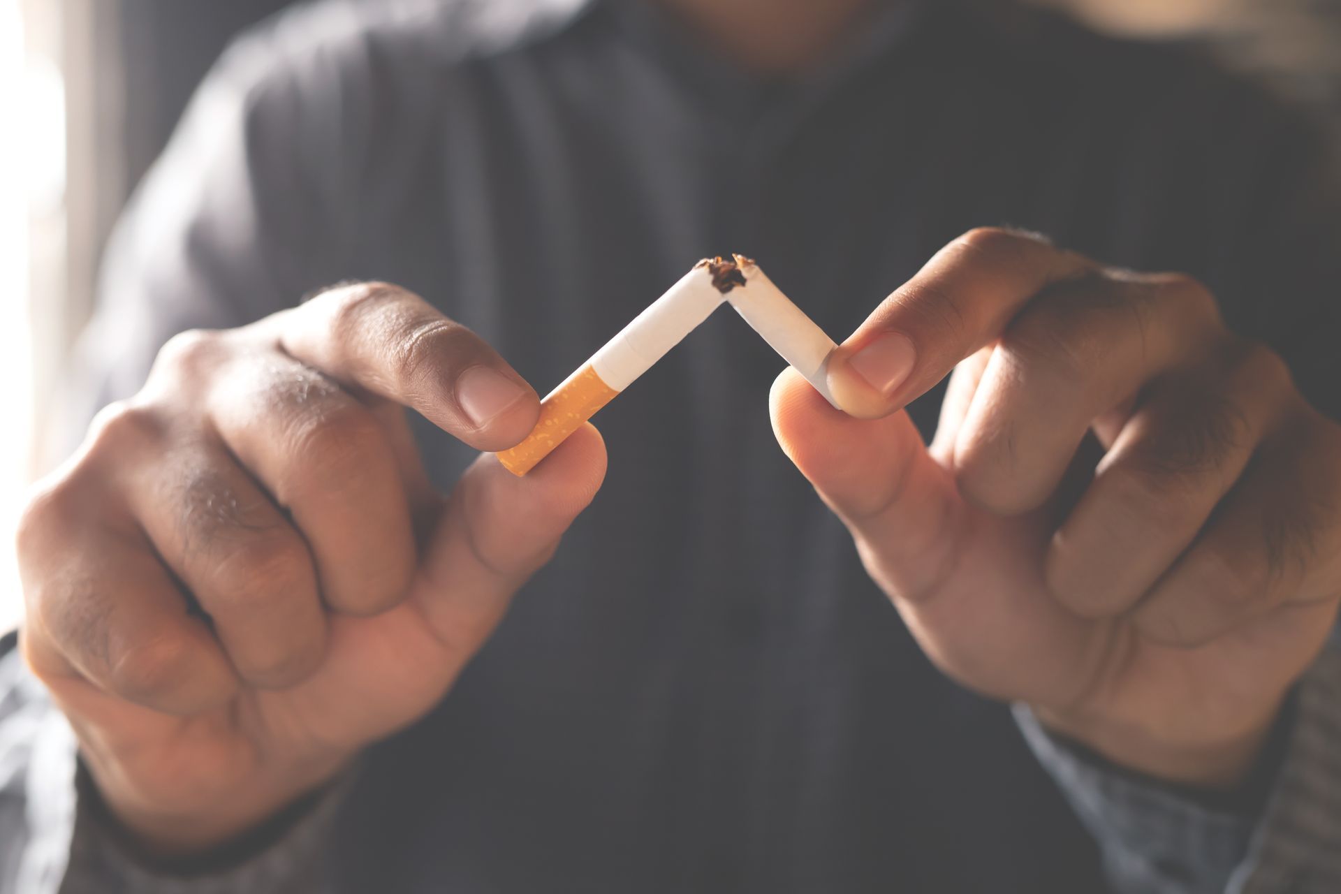 Hands breaking a cigarette in half.