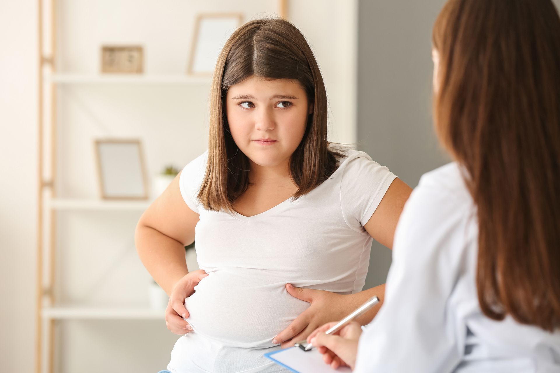 Young person with stomach pain consults with a doctor.