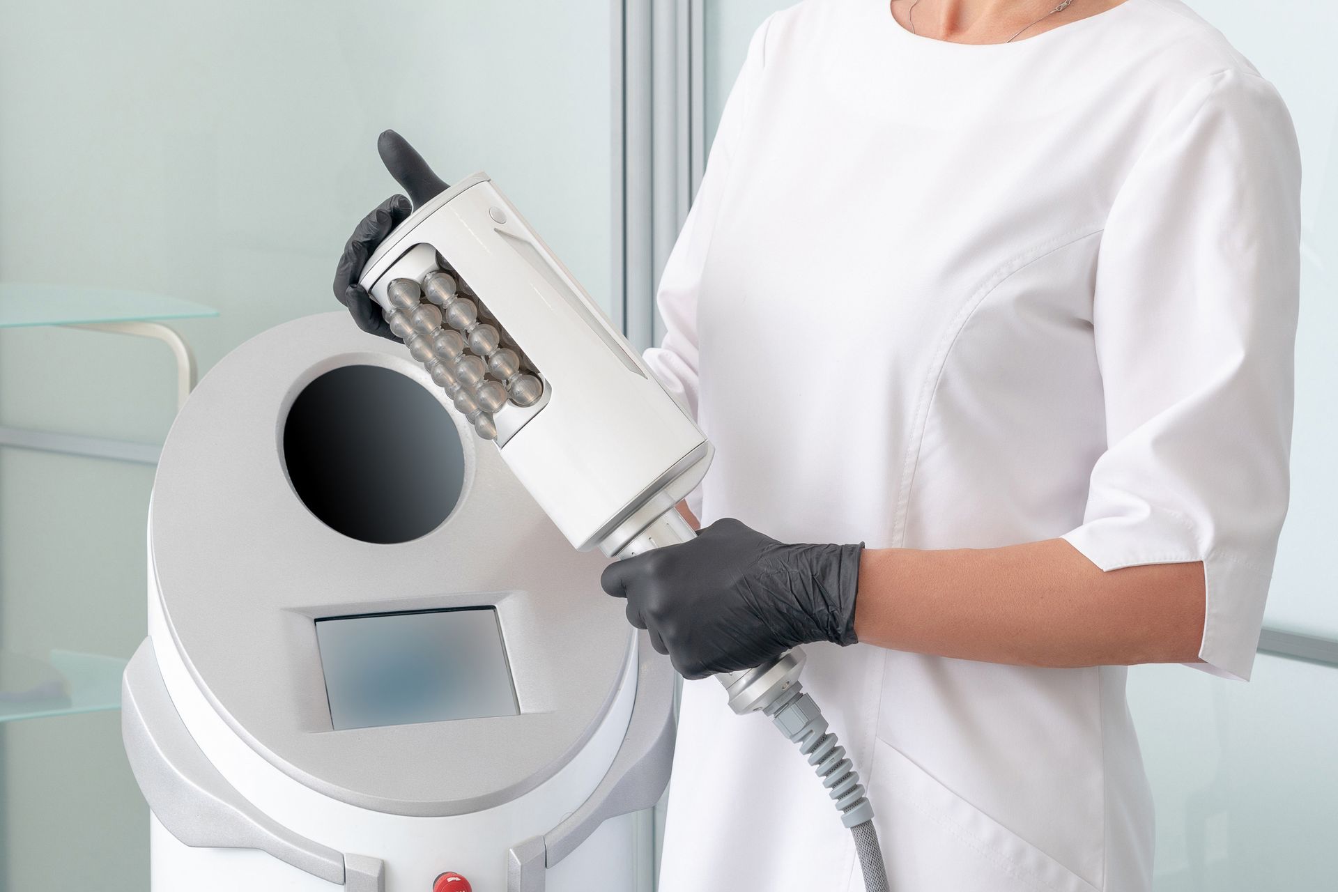 Gloved hand using a massage device on a person’s bare abdomen during a spa treatment