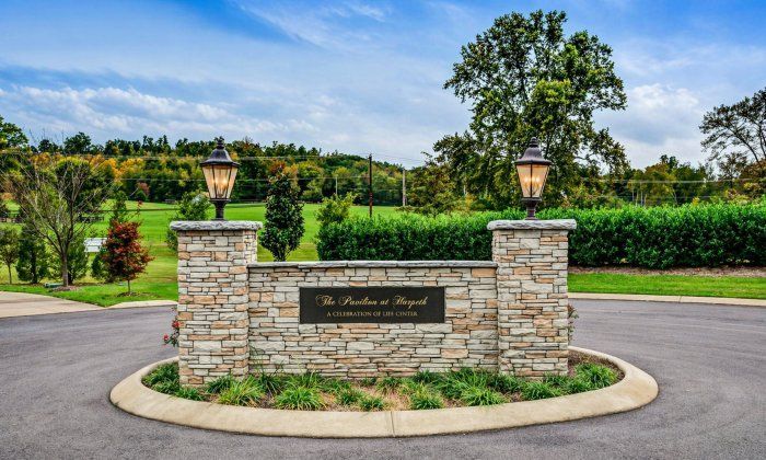 Entrance monument for Fairview, TN Funeral Home and Cremations with stone pillars, lanterns, and greenery