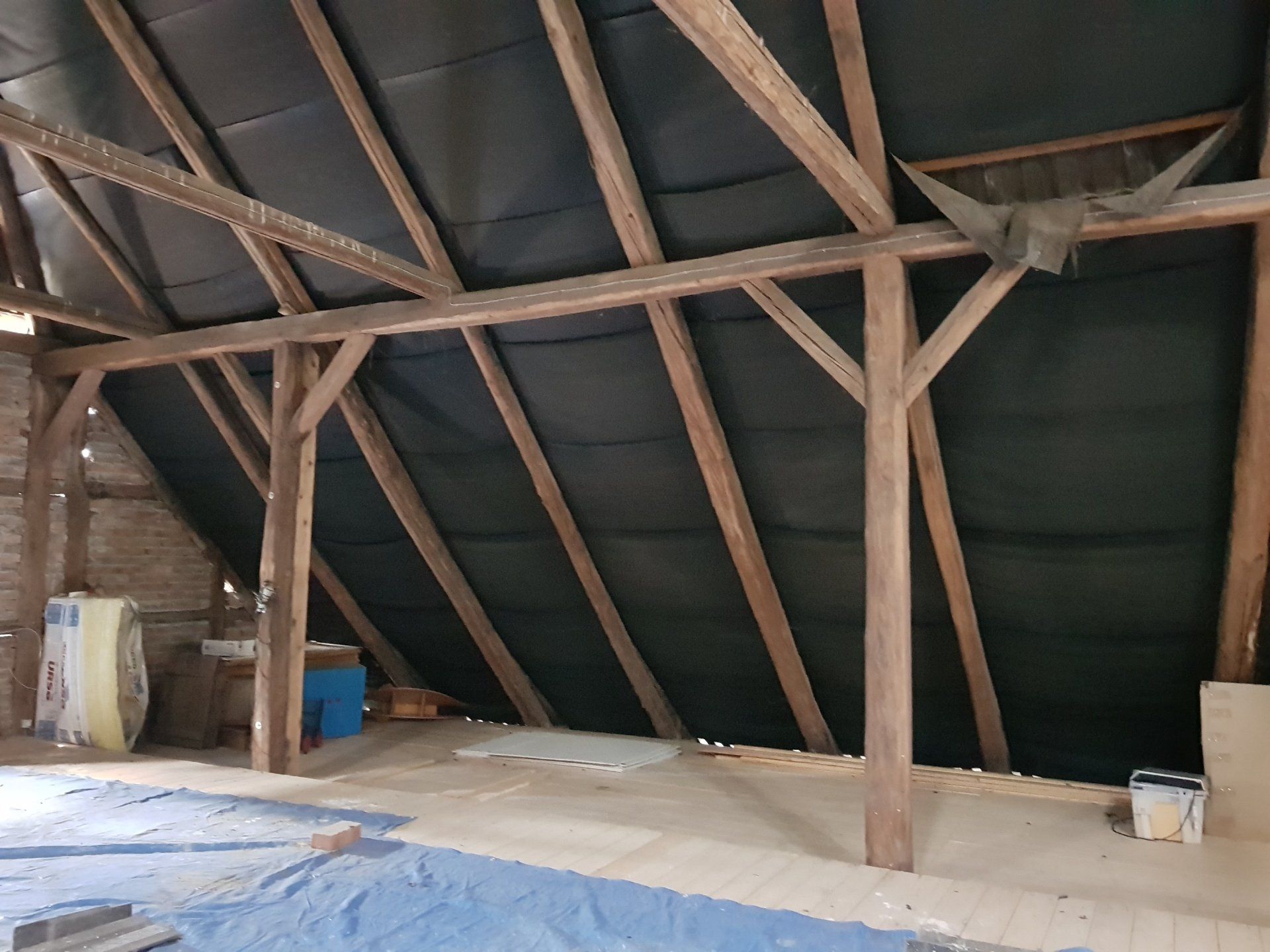 Ein Raum mit einer Holzdecke und einer blauen Plane auf dem Boden.