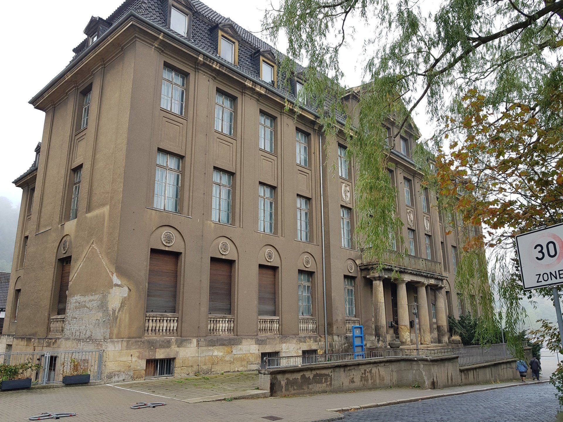 Am Straßenrand steht ein großes Gebäude mit vielen Fenstern.
