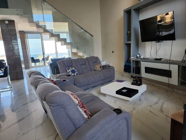A modern, high-ceiling living room with gray sectionals, a white coffee table for Ibogaine treatment
