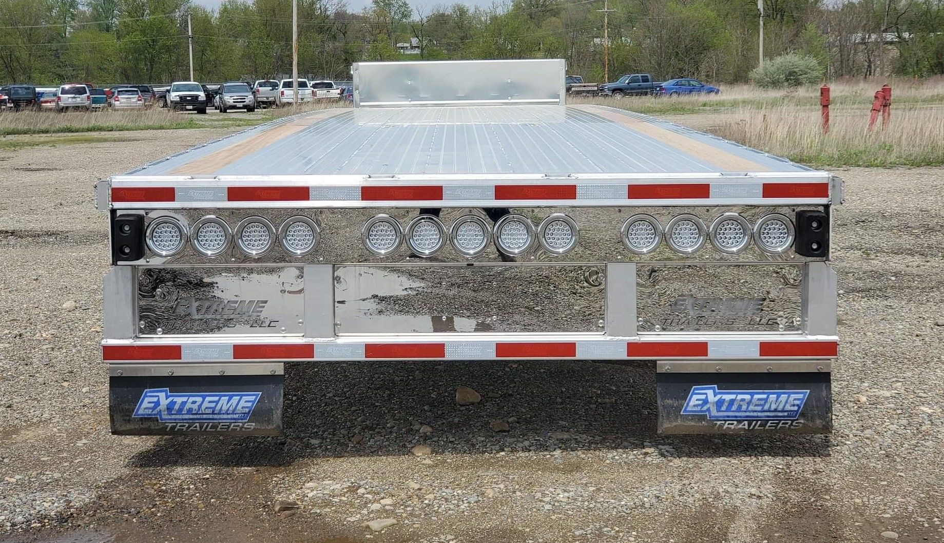 Rear view of a flatbed trailer with chrome and red reflective detailing. 