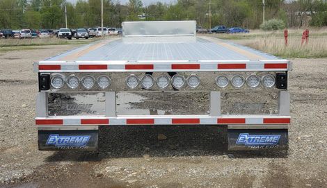 Rear view of a flatbed trailer with chrome and red reflective detailing. 
