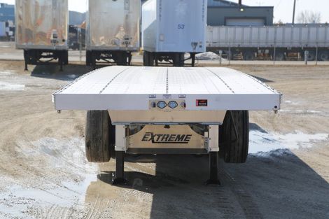 Flatbed trailer with white bed, black tires, and 