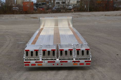 Flatbed trailer, aluminum and wood deck, parked on asphalt. Rear view, red lights visible.