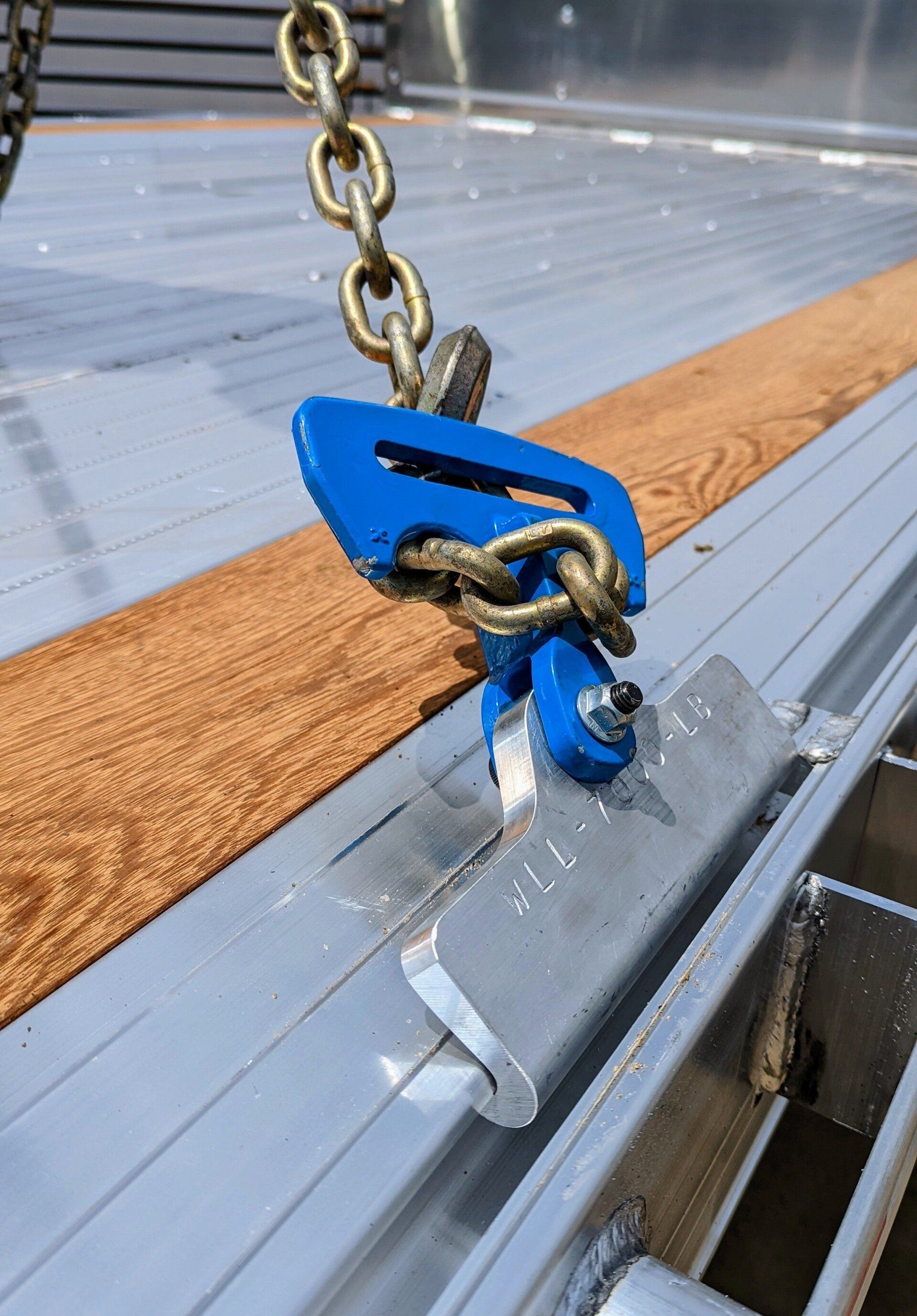 Blue chain binder securing cargo to a metal trailer bed.