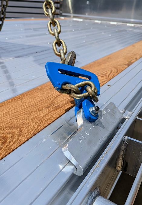 Blue chain binder securing cargo to a metal trailer bed.