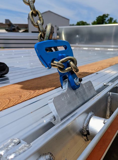Blue chain hook secured to a metal rail, part of a lifting system.