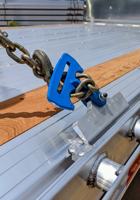 Blue chain binder securing a chain to a flatbed trailer.