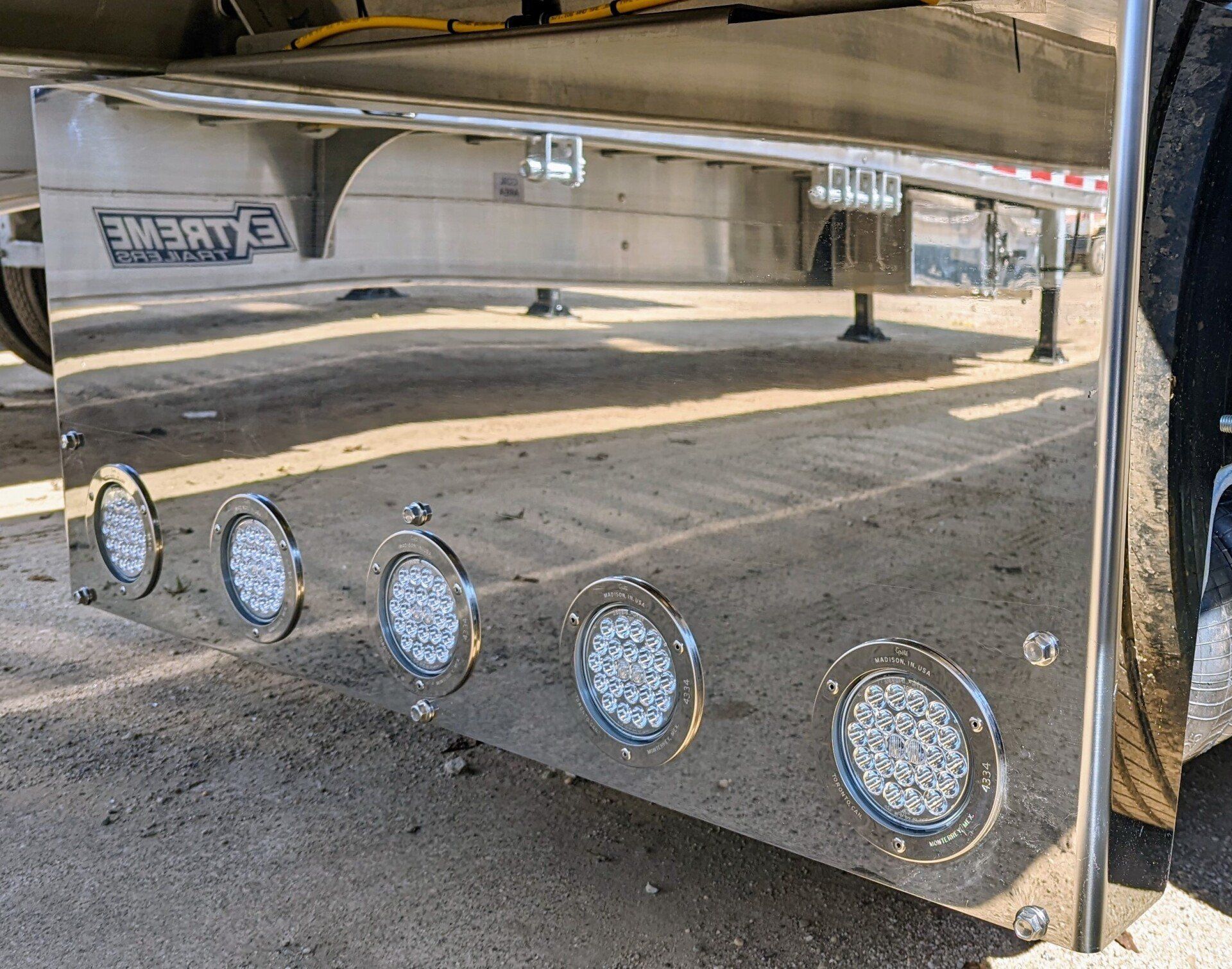 Shiny chrome mud flap with five LED lights on a semi-trailer.