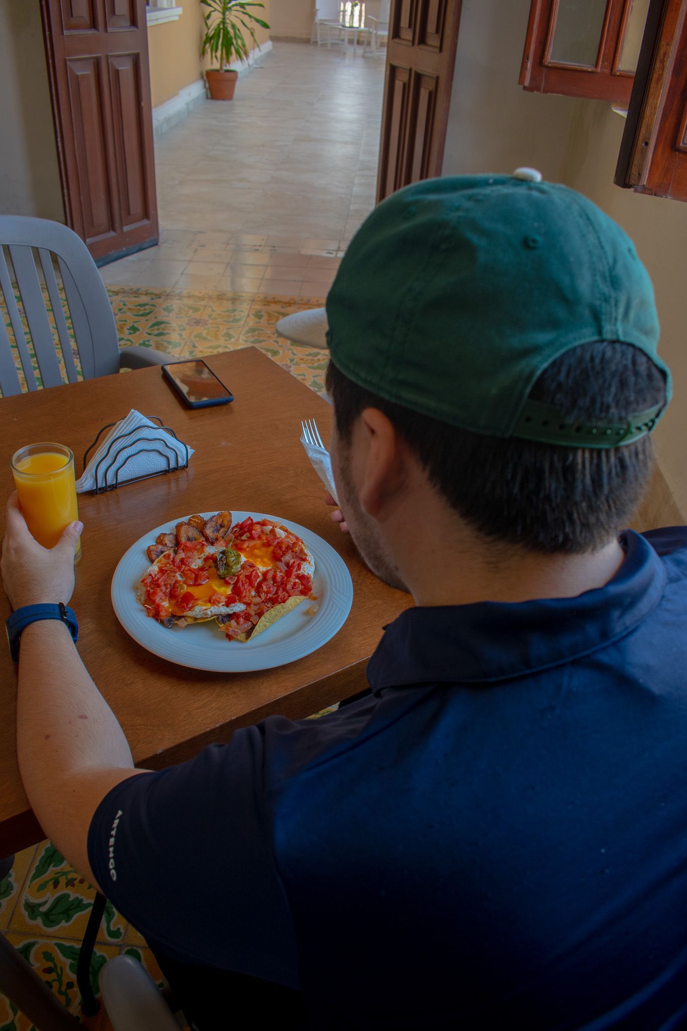 Un hombre está sentado en una mesa comiendo pizza y bebiendo jugo de naranja.