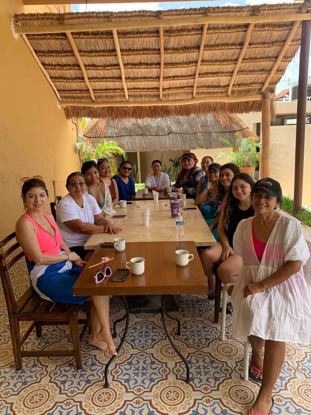 Un grupo de personas están sentadas alrededor de una mesa bajo un techo de paja.