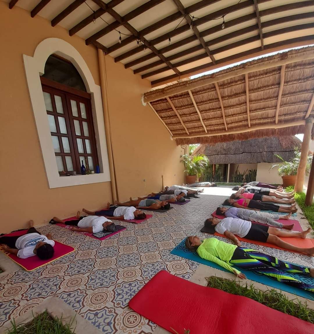 Un grupo de personas están tumbadas sobre colchonetas de yoga bajo un techo.