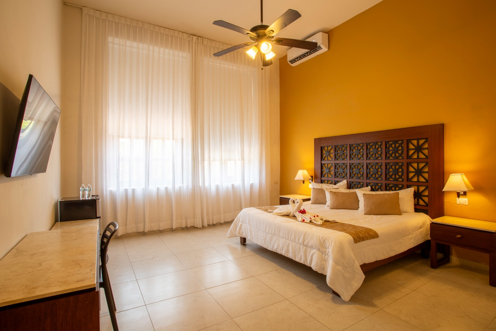 Una habitación de hotel con una cama tamaño king y un ventilador de techo.