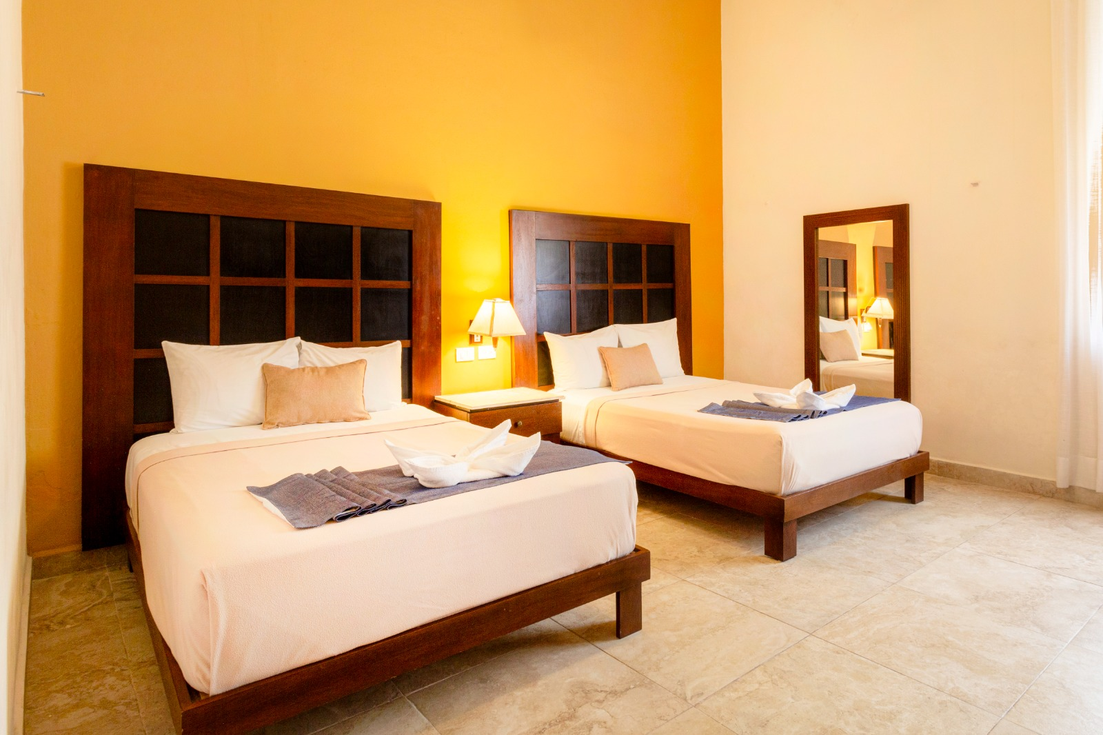Una habitación de hotel con dos camas y un espejo.