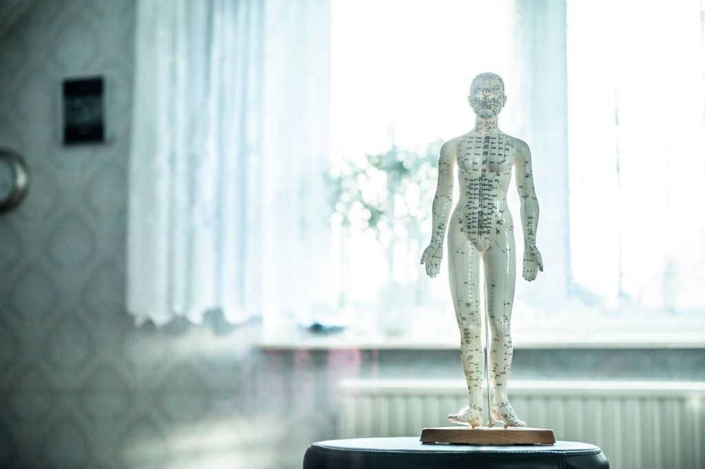 A statue of a human body with acupuncture points on it is sitting on top of a table.