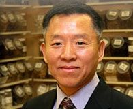 A man in a suit and tie is standing in front of a shelf of herbs.