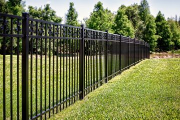 A Black Metal Fence Surrounds A Lush Green Field — Rabbo's Fencing Services In Berry Springs, NT
