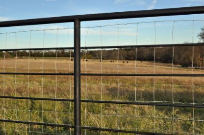 A Fence With A Field In The Background — Rabbo's Fencing Services In Berry Springs, NT