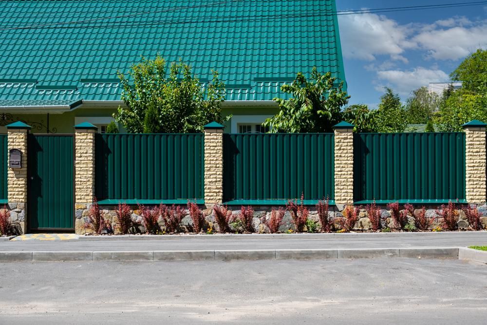 A Green Fence Is In Front Of A House With A Green Roof — Rabbo's Fencing Services In Palmerston, NT