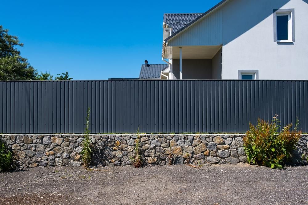 A House With A Stone Wall And A Fence In Front Of It — Rabbo's Fencing Services In Humpty Doo, NT