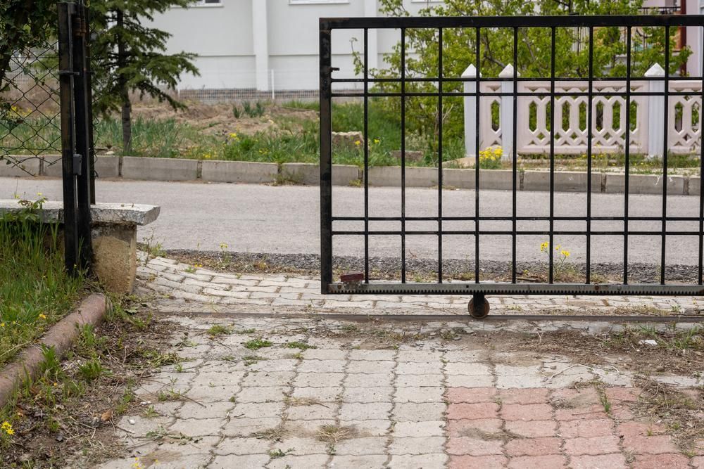 A Sliding Gate Is Open To A Brick Driveway — Rabbo's Fencing Services In Casuarina, NT