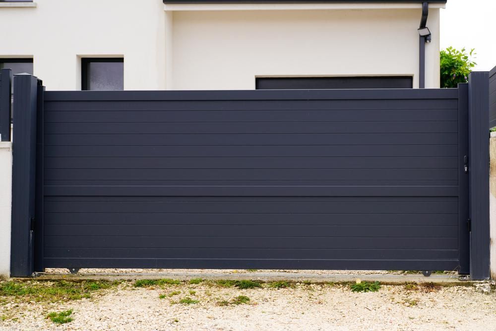 A Black Sliding Gate Is In Front Of A White House — Rabbo's Fencing Services In Berry Springs, NT