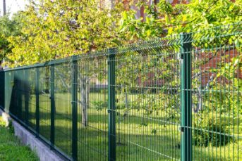 A Green Wire Fence Surrounds A Lush Green Yard — Rabbo's Fencing Services In Berry Springs, NT