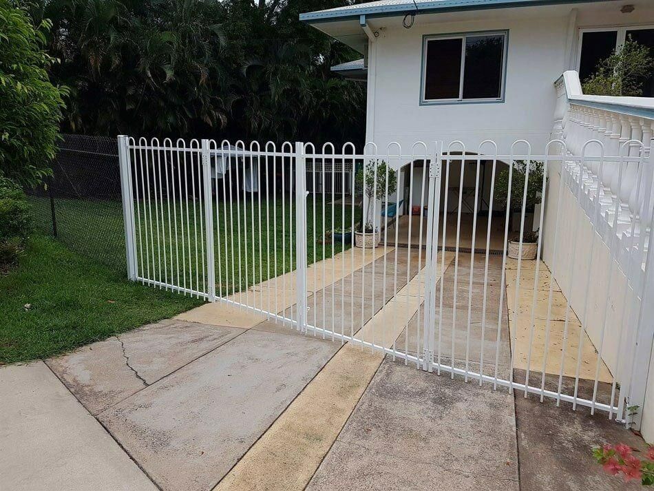 A White Fence Surrounds A Driveway Leading To A House — Rabbo's Fencing Services In Pinelands, NT