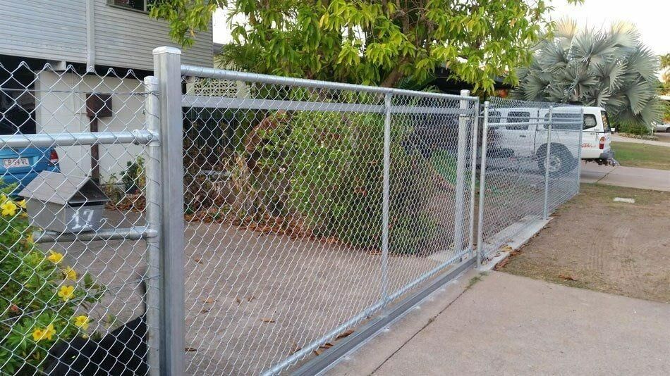 A Chain Link Fence With A Sliding Gate In Front Of A House — Rabbo's Fencing Services In Pinelands, NT