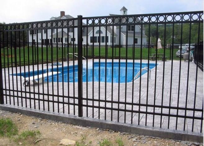 A Black Metal Fence Surrounds A Swimming Pool — Rabbo's Fencing Services In Pinelands, NT