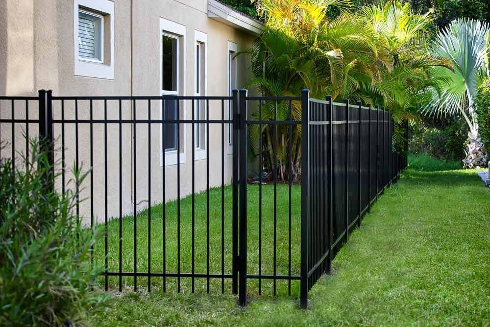 A Black Metal Fence With A Gate In Front Of A House — Rabbo's Fencing Services In Pinelands, NT
