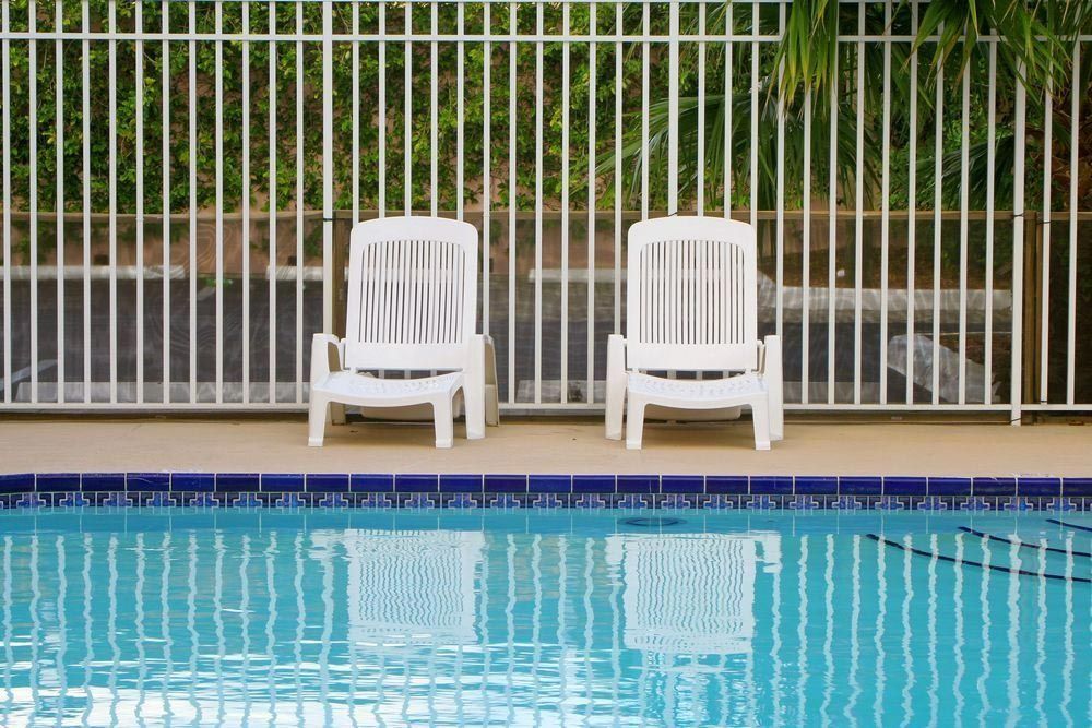 Two White Chairs Are Sitting Next To A Swimming Pool — Rabbo's Fencing Services In Pinelands, NT