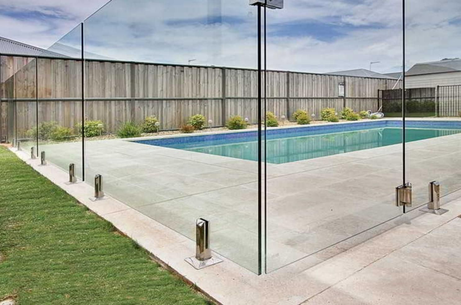 A Swimming Pool Surrounded By A Glass Fence And A Wooden Fence — Rabbo's Fencing Services In Pinelands, NT